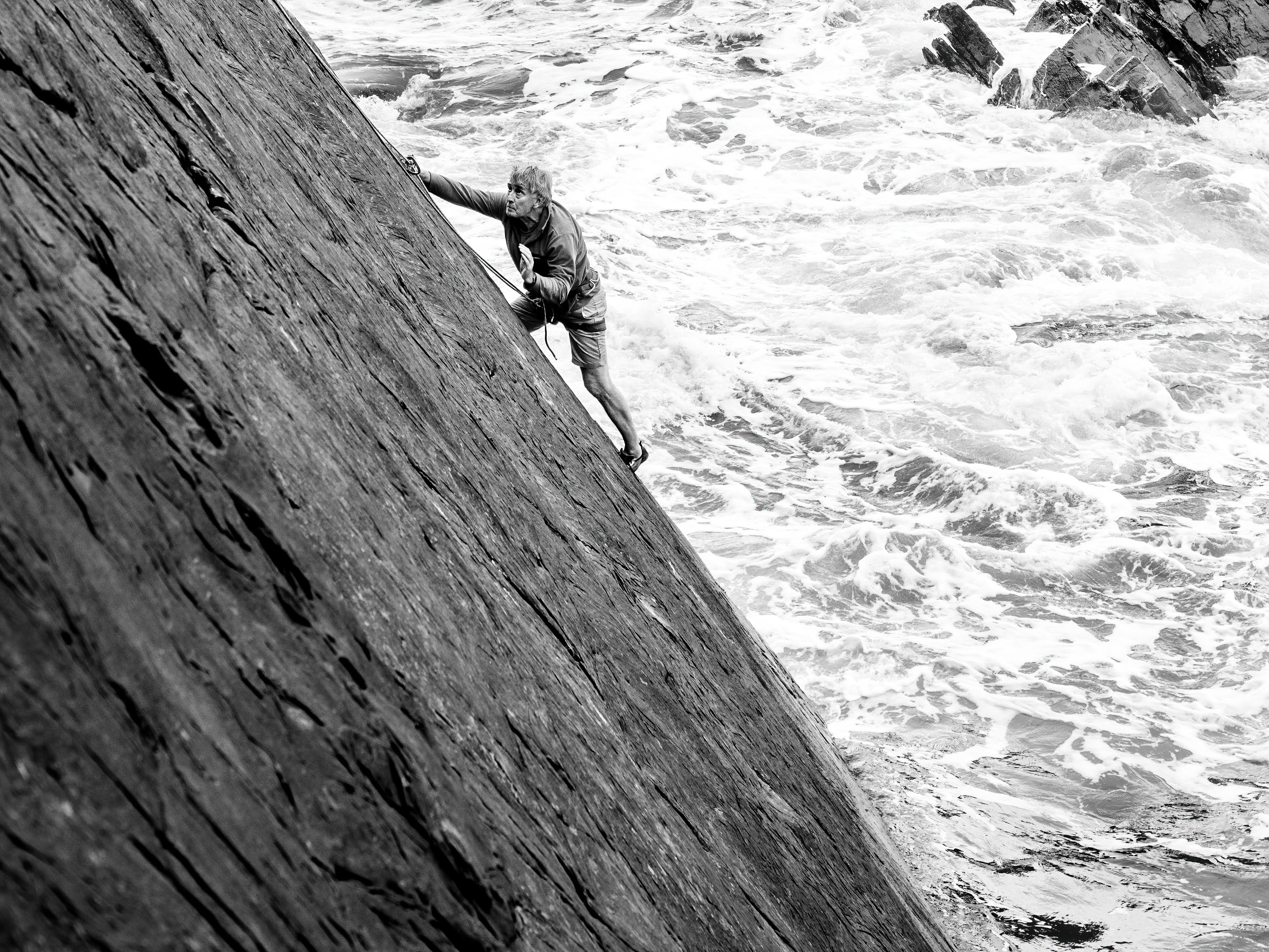 A black-and-white photograph of Iain Peters climbing